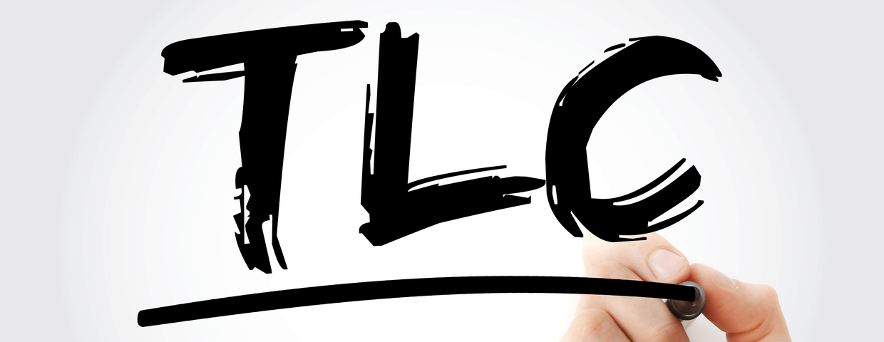 Hand holding pen writing TLC - Tender Loving Care acronym, concept background